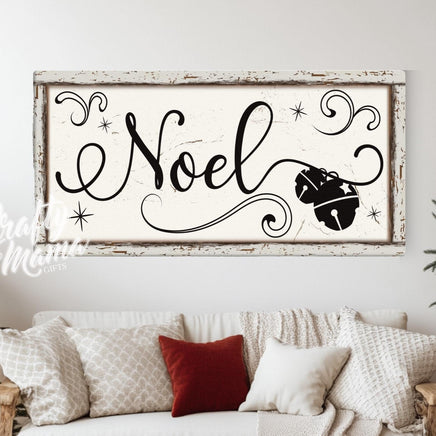 Noel Christmas sign above a white couch sitting next to a christmas tree