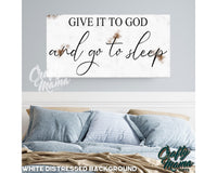 a bed with pillows and a sign above it that says give it to god and