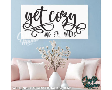 a living room with a pink couch and a sign that says get cozy and stay