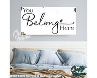 a picture of a bed with pillows and a sign that says you belong here