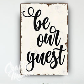 a sign that says be our guest hanging on a wall