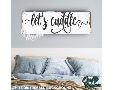 a bed with pillows and a wooden sign that says let&#39;s cuddle