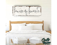 a bed with white linens and a wooden sign above it