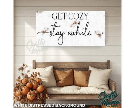 a picture of a couch with pillows and a sign that says get cozy stay awhile