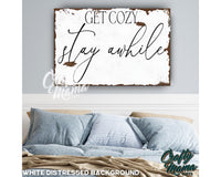 a bedroom with a bed and a sign that says get cozy stay awhile