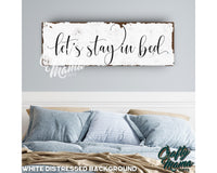 a bed with a wooden sign above it that says let&#39;s stay in bed