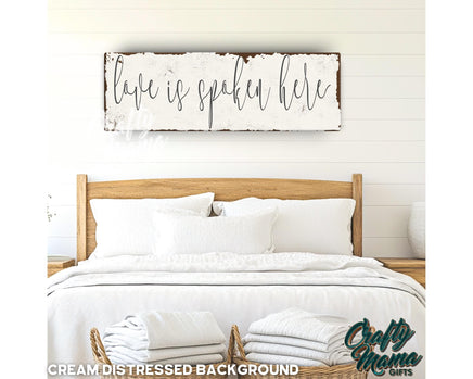 a bed with white linens and a wooden sign above it