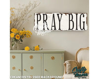 a sign that says pray big above a dresser