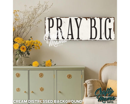 a sign that says pray big above a dresser