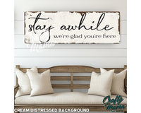 a wooden sign that says stay awhile, we&#39;re glad you&#39;re here